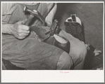 Nailing foot of boot to sole, in order to hold in place when sewing foot to welt. These nails are removed after sewing. Bootmaking shop, Alpine, Texas