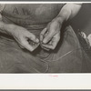 Threading a needle with waxed thread. Bootmaking shop, Alpine, Texas
