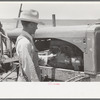 Day laborer cranking tractor on farm near Ralls, Texas