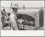Day laborer cranking tractor on farm near Ralls, Texas