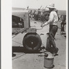 Day laborer cranking tractor on farm near Ralls, Texas