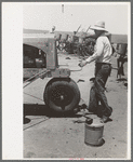 Day laborer cranking tractor on farm near Ralls, Texas