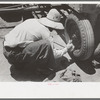 Day laborer putting in cotter pin in front of tractor, farm near Ralls, Texas