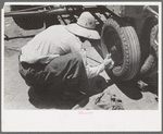 Day laborer putting in cotter pin in front of tractor, farm near Ralls, Texas