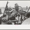 Son of day laborer sitting in tractor seat, large farm near Ralls, Texas