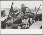 Son of day laborer sitting in tractor seat, large farm near Ralls, Texas