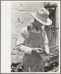 Day laborer looking through box of nuts and bolts, farm near Ralls, Texas