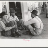 Farmers sitting against wall and squatting on sidewalk, Spur, Texas
