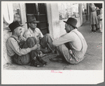 Farmers sitting against wall and squatting on sidewalk, Spur, Texas