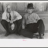 Farmers sitting against wall and squatting on sidewalk, Spur, Texas