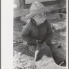 Little boy cutting up inner tube, El Indio, Texas