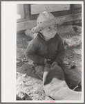 Little boy cutting up inner tube, El Indio, Texas