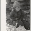 Little boy cutting up inner tube, El Indio, Texas