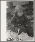 Little boy cutting up inner tube, El Indio, Texas