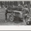 White migrant strawberry picker unloading automobile cushion springs from trailer. These will be used as bed springs. Hammond, Louisiana