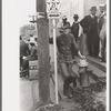 Farmer leaning on post and fire hydrant at street corner, San Augustine, Texas