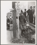 Farmer leaning on post and fire hydrant at street corner, San Augustine, Texas