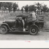 Migrant getting out of car with pail to get some water. Encamped along roadside near Henrietta, Oklahoma