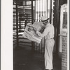 Man reading newspaper while waiting for streetcar. Streetcar station, Oklahoma City, Oklahoma