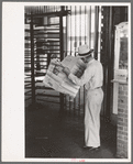 Man reading newspaper while waiting for streetcar. Streetcar station, Oklahoma City, Oklahoma