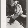 Mr. Johnson, FSA client with part interest in cooperative well, putting on his boots near Syracuse, Kansas