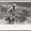 Mr. Johnson, FSA client with part interest in cooperative well using a makeshift dam of tumbleweeds and board in order to divert water from irrigation ditch to field, Syracuse, Kansas