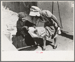 Seventy-five-year-old Spanish-Aamerican woman taking loaf of bread to place in outdoor earthern oven for baking, Taos County, N.M