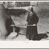 Spanish-American woman testing temperature of earthen oven by determining length of time required to scorch wool. Taos County, New Mexico