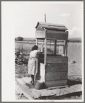 Daughter of Spanish-American farm family drawing water at the well, Taos County, New Mexico