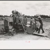 Dumping materials into concrete mixer at migrant camp under construction at Sinton, Texas