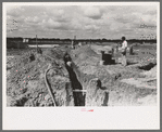 Laying sewer pipe at migrant camp under construction at Sinton, Texas