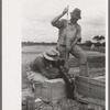 Workman checking measurements against migrant camp under construction at Sinton, Texas