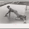 Smoothing concrete floor at migrant camp under construction at Sinton, Texas