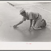 Smoothing concrete floor at migrant camp under construction at Sinton, Texas