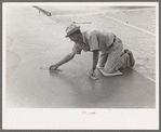 Smoothing concrete floor at migrant camp under construction at Sinton, Texas