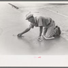 Smoothing concrete floor at migrant camp under construction at Sinton, Texas