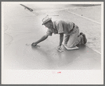 Smoothing concrete floor at migrant camp under construction at Sinton, Texas