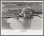 Smoothing concrete floor in construction of migrant camp, Sinton, Texas