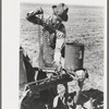 Day laborer putting chain onto feeder gear of planter on farm near Ralls, Texas