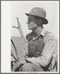 Day laborer sitting in tractor seat, large farm near Ralls, Texas