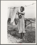 Daughter of tenant farmer hanging up clothes near Warner, Oklahoma