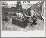 Veteran migrant agricultural worker examining contents of his trunk, camped on Arkansas River in Wagoner County, Oklahoma