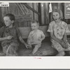 Children of agricultural day laborers sitting on bench in front of small store near Vian, Oklahoma