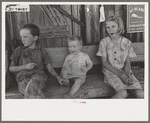 Children of agricultural day laborers sitting on bench in front of small store near Vian, Oklahoma