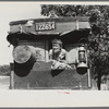 White migrant child sitting in back seat of family car east of Fort Gibson, Muskogee County, Oklahoma