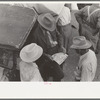 Farmers talking and looking at tire sale handbill, Weatherford, Texas