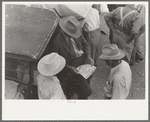 Farmers talking and looking at tire sale handbill, Weatherford, Texas
