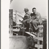 Stockmen sitting on fence at stockyard, San Angelo, Texas