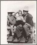 West Texan and his son sitting on fence at horse auction, El Dorado, Texas