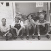 Men sitting along sidewalk in farm marketing section of Muskogee, Oklahoma